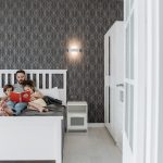 Father and children enjoy a bonding storytime in a cozy, modern bedroom setting.