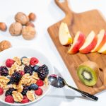 A nutritious breakfast bowl featuring fresh berries and walnuts, served with sliced fruit and kiwi.